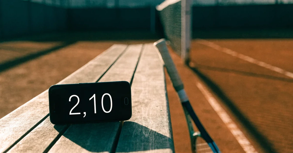 Uma bola de futebol no ponto central de um relvado, à luz da manhã